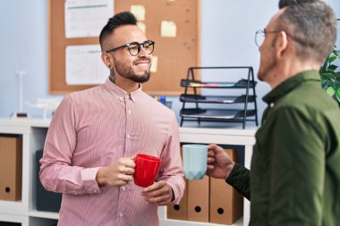 Two men business workers smiling confident drinking coffee at office
