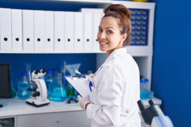Young woman scientist writing on document working at laboratory