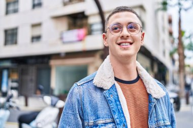 Young hispanic man smiling confident looking to the side at street