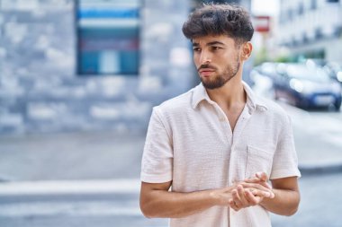 Genç Arap adam sokakta rahat bir ifadeyle yan tarafa bakıyor.