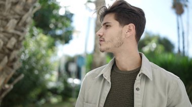 Genç İspanyol bir adam parkta ciddi bir ifadeyle yan tarafa bakıyor.