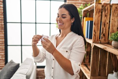 Evinde kablosuz kulaklıkla gülümseyen güzel bir İspanyol kadın.