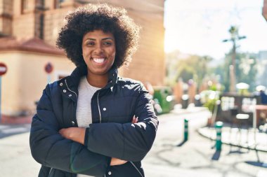 Sokakta kollarını kavuşturmuş Afro-Amerikalı bir kadın.