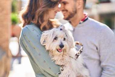 Man and woman holding dog standing together at street
