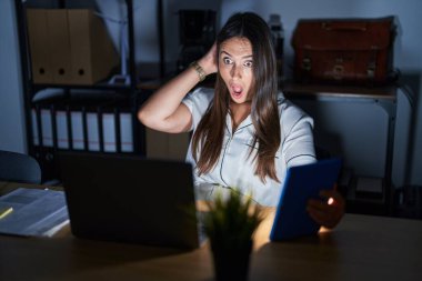 Geceleri ofiste çalışan genç esmer kadın deli ve elleri başının üstünde korkmuş, ağzı açık şoktan korkmuş ve şaşırmış. 