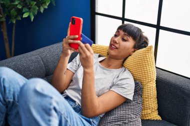 Genç kadın evde koltukta yalan smartphone kullanarak