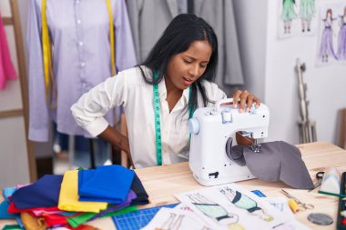 Terzide dikiş makinesi kullanan genç ve güzel bir kadın.