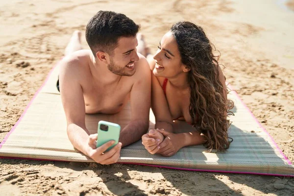 Young Hispanic Couple Tourists Wearing Swimsuit Using Smartphone Seaside — Stockfoto