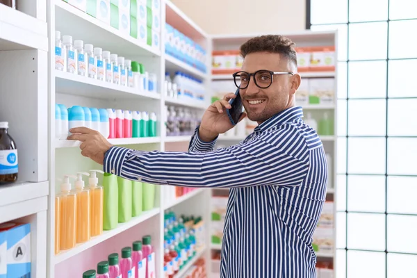 Jovem Hispânico Homem Cliente Falando Smartphone Segurando Produto Prateleira Farmácia — Fotografia de Stock