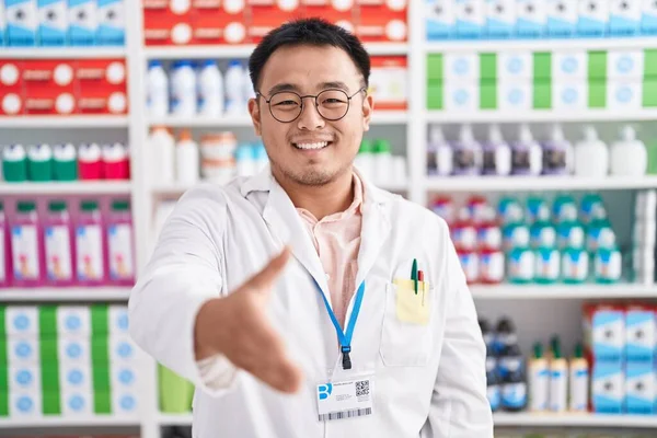 薬局で働く中国の若者は 挨拶や歓迎として握手を提供しています 成功したビジネス — ストック写真