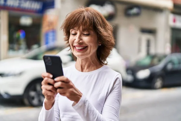 stock image Middle age woman smiling confident using smartphone at street