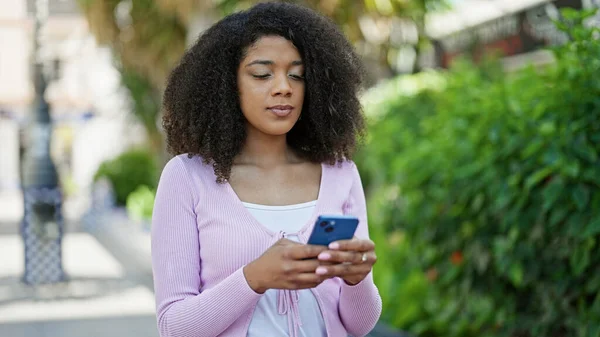stock image African american woman using smartphone with serious expression at park
