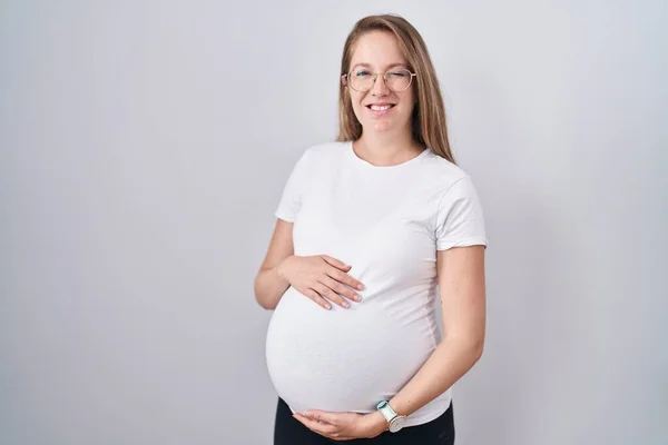 年轻的孕妇在等着孩子 一边摸着怀孕的肚子一边眨着眼睛 一边带着性感的表情 开心而快乐地看着摄像机 — 图库照片