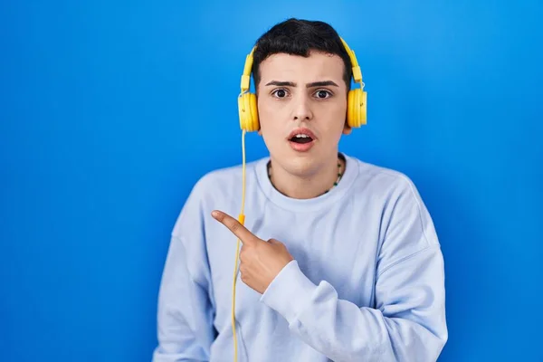 Δυαδικό Πρόσωπο Που Ακούει Μουσική Χρησιμοποιώντας Ακουστικά Έκπληκτος Δείχνοντας Δάχτυλο — Φωτογραφία Αρχείου