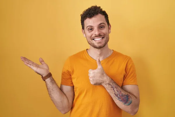 Young Hispanic Man Standing Yellow Background Showing Palm Hand Doing — Fotografia de Stock