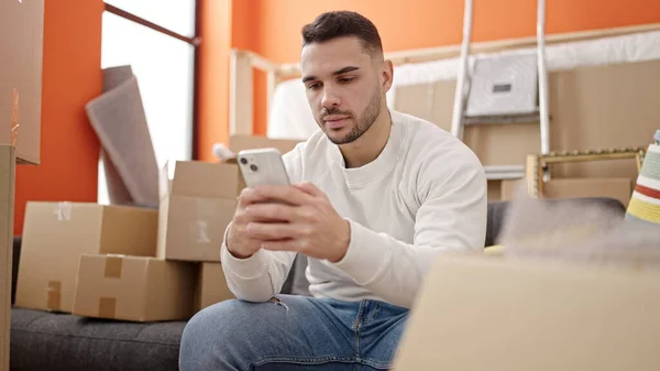 Junger Hispanischer Mann Sitzt Mit Smartphone Auf Sofa Neuen Zuhause — Stockfoto