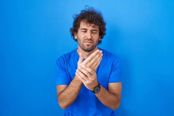 Homem Jovem Hispânico Sobre Fundo Azul Sofrendo Dor Nas Mãos — Fotografia de Stock