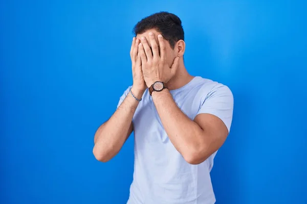 Homem Hispânico Jovem Sobre Fundo Azul Com Expressão Triste Cobrindo — Fotografia de Stock
