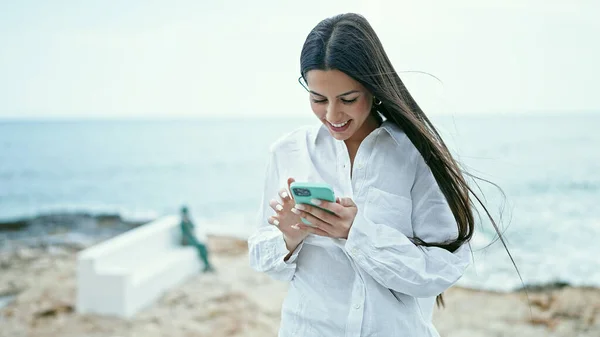 Młoda Piękna Latynoska Kobieta Pomocą Smartfona Uśmiechnięta Nad Morzem — Zdjęcie stockowe