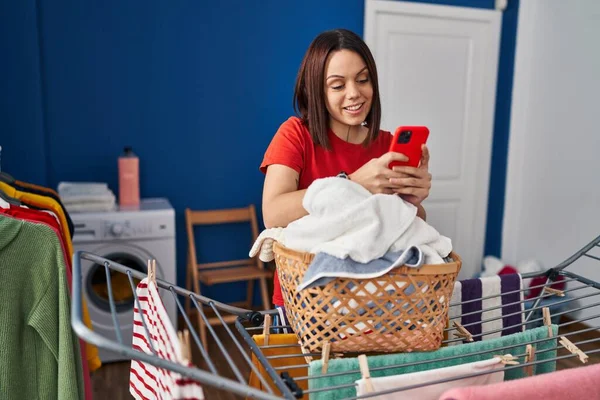 Young Beautiful Hispanic Woman Using Smartphone Hanging Clothes Clothesline Laundry — Stok fotoğraf