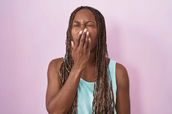 站在粉色背景上的非洲裔美国女人厌烦了打呵欠 疲倦得用手捂住嘴 烦躁不安和困倦 — 图库照片