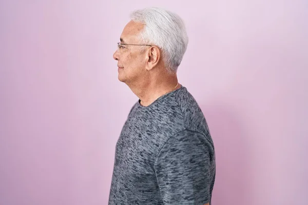 Мужчина Среднего Возраста Седыми Волосами Стоящими Розовом Фоне Глядя Сторону — стоковое фото