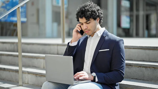 Young Latin Man Business Worker Using Laptop Talking Smartphone Street — Stockfoto