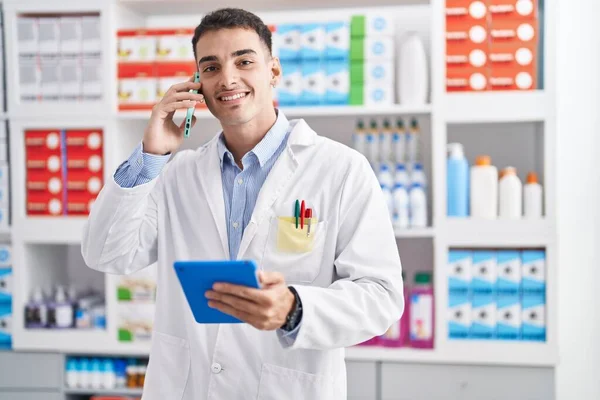 Joven Farmacéutico Hispano Hablando Smartphone Usando Touchpad Farmacia —  Fotos de Stock