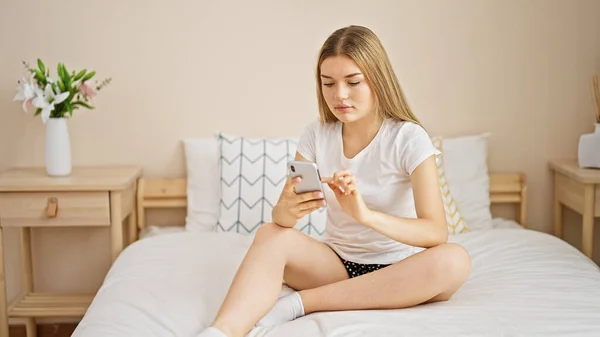 Νεαρή Ξανθιά Γυναίκα Που Χρησιμοποιεί Smartphone Κάθεται Στο Κρεβάτι Στο — Φωτογραφία Αρχείου