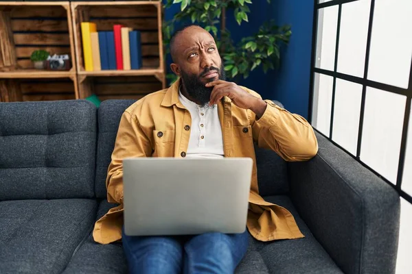 Afroamerikansk Man Använder Laptop Hemma Sitter Soffan Allvarliga Ansikte Tänker — Stockfoto