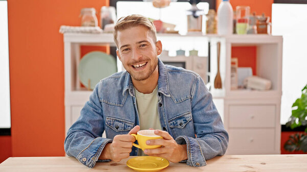 Young caucasian man drinking coffee sitting on table speaking at dinning room