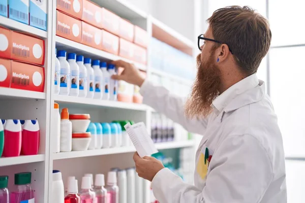 Young Redhead Man Pharmacist Reading Prescription Pharmacy — Stock Photo, Image