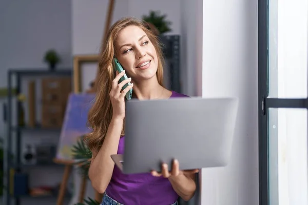 Young Blonde Woman Artist Talking Smartphone Using Laptop Art Studio — Stock Photo, Image