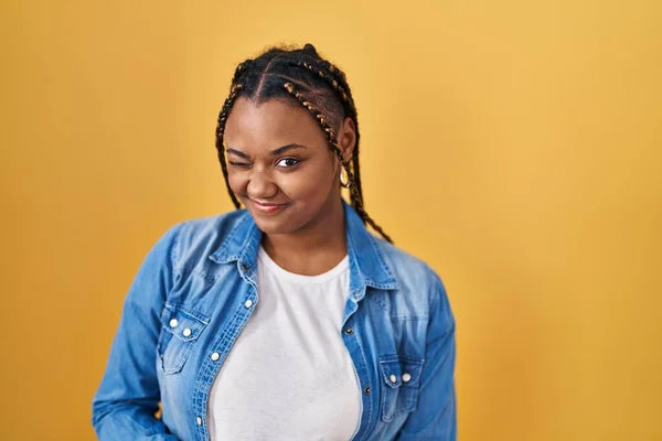 African American Woman Braids Standing Yellow Background Winking Looking Camera — Stock Photo, Image