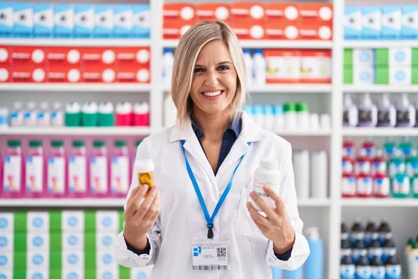 Young Blonde Woman Pharmacist Smiling Confident Holding Pills Bottles Pharmacy — Foto Stock