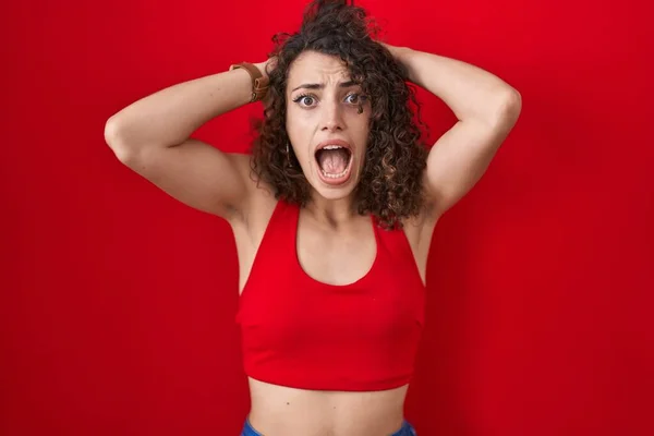 Mulher Hispânica Com Cabelos Encaracolados Sobre Fundo Vermelho Louco Assustado — Fotografia de Stock
