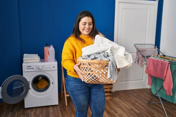 Young Beautiful Size Woman Smiling Confident Holding Basket Clothes Laundry — Zdjęcie stockowe