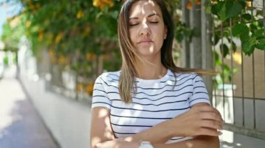 Orta Doğulu bir kadın sokakta çapraz kollarla gülümsüyor.