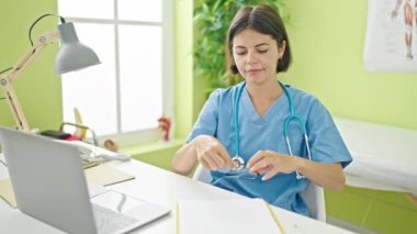 Genç, güzel İspanyol kadın doktor klinikte gözlük takarak gülümsüyor.