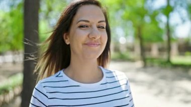 Ortadoğulu kadın parkta kendinden emin gülümsüyor.