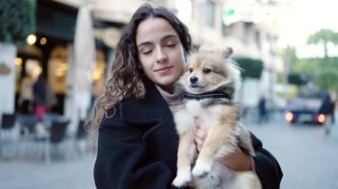 Köpeğiyle gülümseyen, sokakta kendine güvenen genç İspanyol kadın.