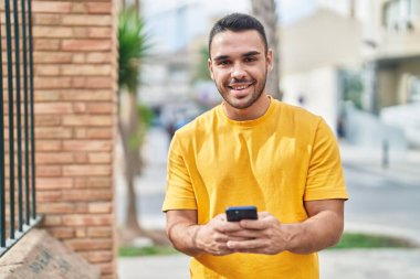 Sokakta akıllı telefon kullanan, kendine güvenen genç bir İspanyol.