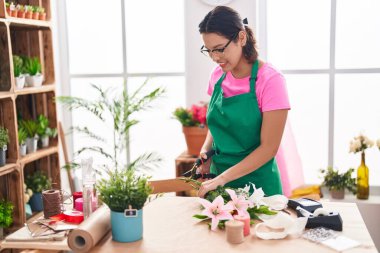 Young hispanic woman florist make bouquet of flowers at florist