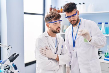 Young couple wearing scientist uniform holding sample at laboratory