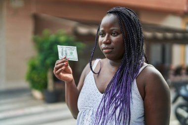 Kafe terasında elinde 100 dolarlık banknot tutan Afrikalı Amerikalı kadın.