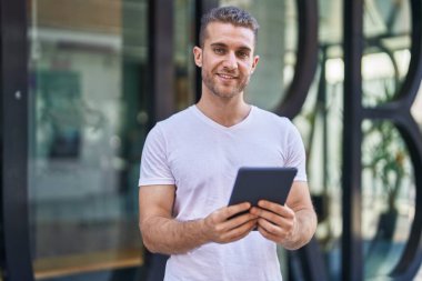 Young caucasian man smiling confident using touchpad at street