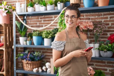 Çiçekçiye akıllı telefon kullanarak gülümseyen güzel İspanyol kadın.