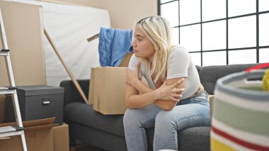 Genç, güzel, İspanyol bir kadın yeni evinde rahat bir ifadeyle koltukta oturuyor.