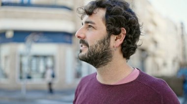 Latin kökenli genç adam ciddi bir ifadeyle sokağa bakıyor.