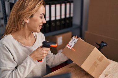 Young woman ecommerce busines worker scanning package at office